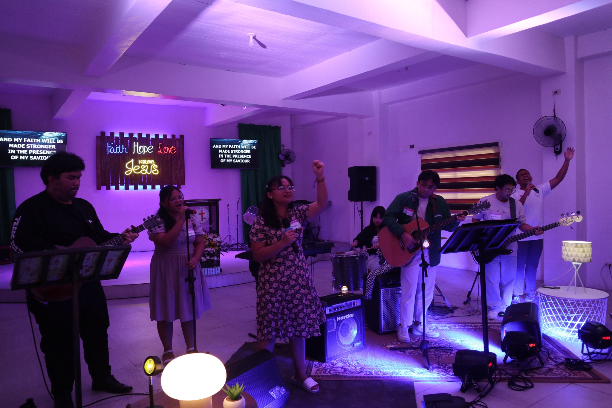 Wide view of the Ignite 2025 band performing together, with singers raising their hands, guitarists, a bassist, and the drummer